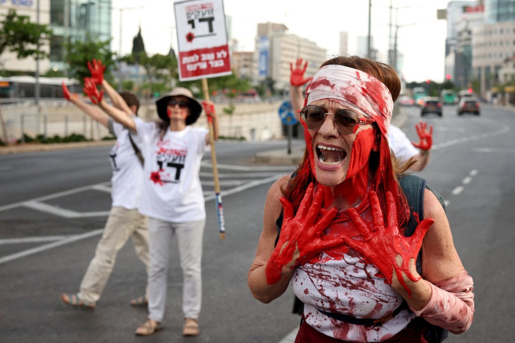 Covered in red paint, mothers of Israeli soldiers serving in the Gaza Strip block a road in Tel Aviv on Wednesday to demand an end to the ongoing conflict. Photo: Reuters