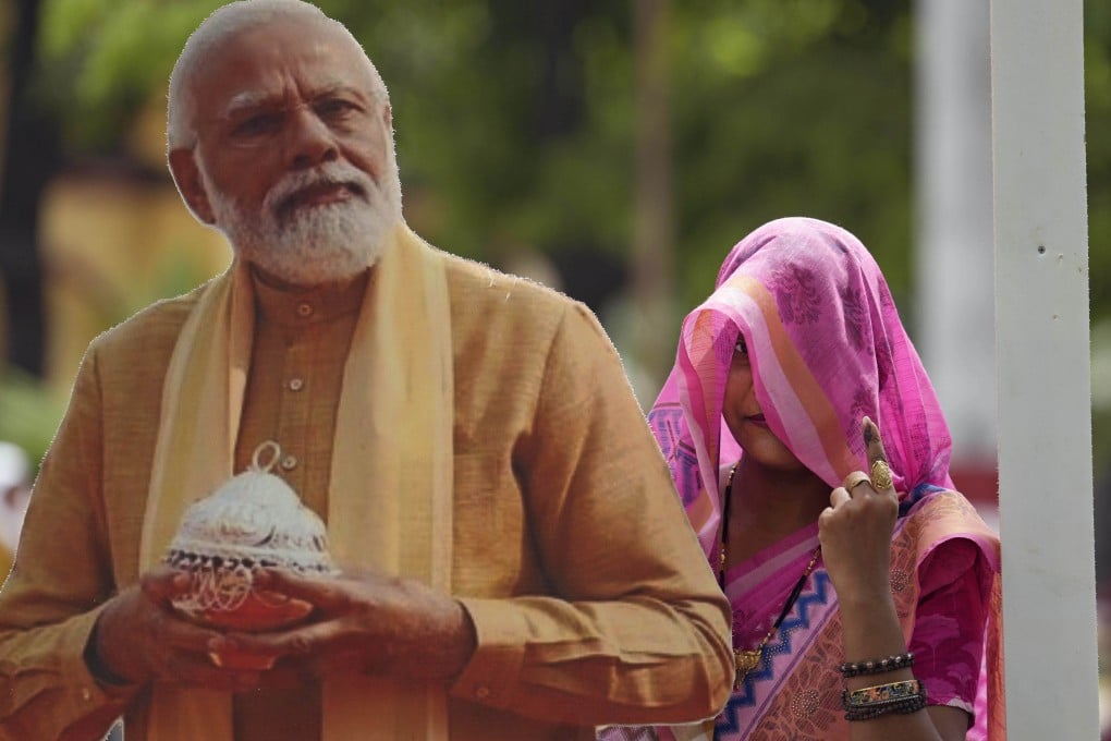 A woman shows her index finger marked with an indelible ink as she poses for a photograph next to a cut-out portrait of Indian Prime Minister Narendra Modi after voting in Varanasi, India, on Saturday. Photo: AP