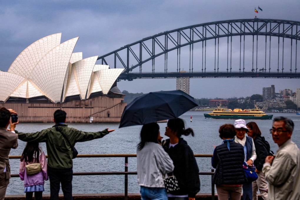 People take in the Sydney Harbour view on a rainy day on December 21, 2023. Photo: AFP