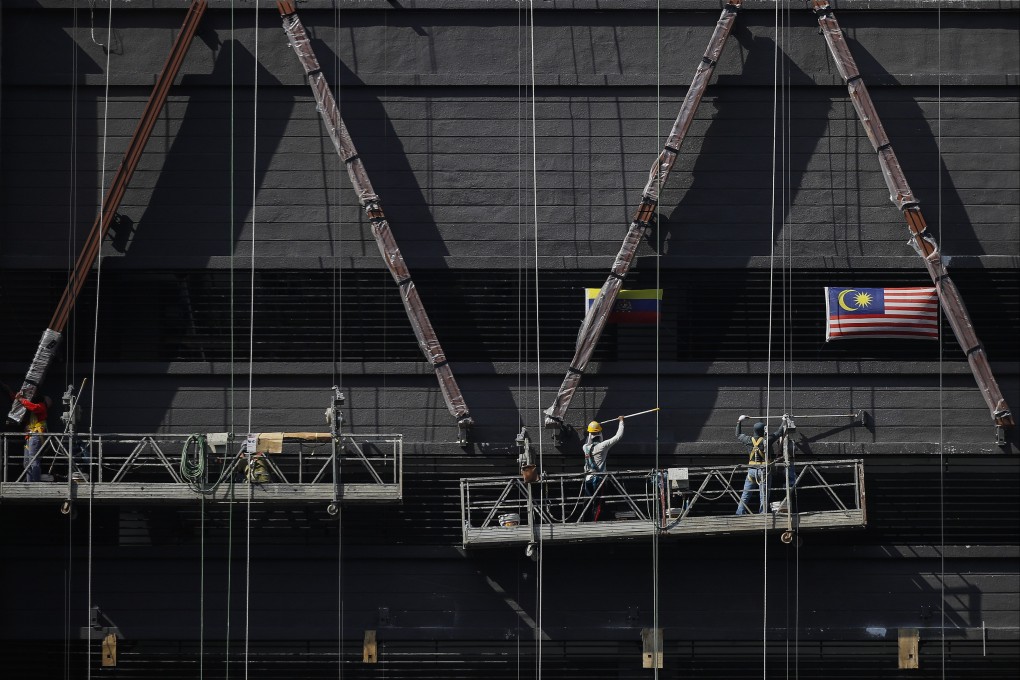 Construction workers paint a building in Kuala Lumpur. Malaysia has been in the spotlight for months over allegations that forced labour, debt bondage and scam jobs have riddled its recruitment market for foreign labour. Photo: EPA-EFE