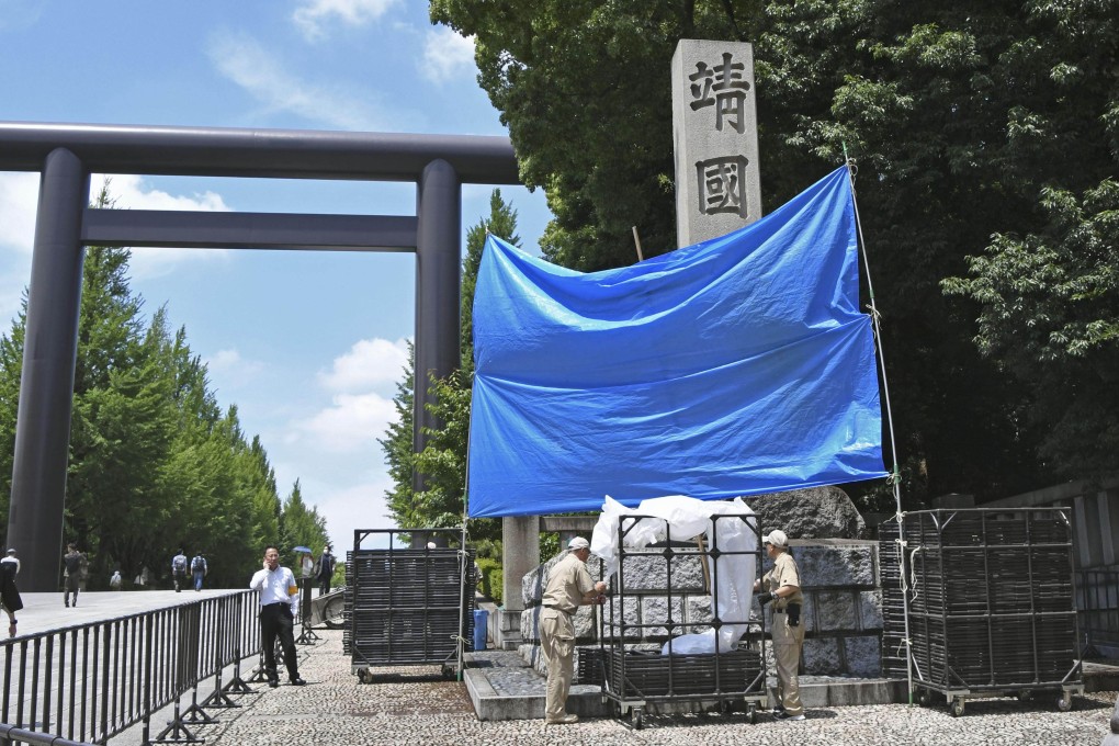 A blue sheet is used to cover a stone pillar at the Yasukuni Shrine in Tokyo on Saturday after graffiti reading “toilet” in English was found on it earlier in the day. Photo: Kyodo