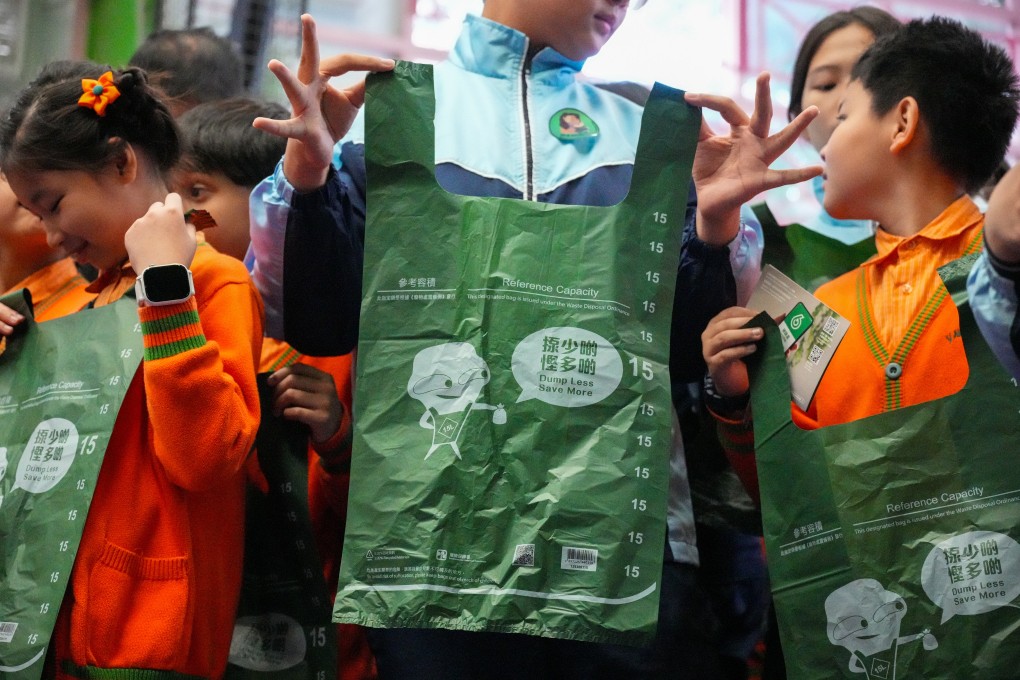 Students hold up designated bags for the waste-charging scheme during a promotional event on January 16. The scheme has been shelved, and the government has pledged to hand out 20 bags for free to every household in public rental flats monthly for half a year. Photo: Eugene Lee