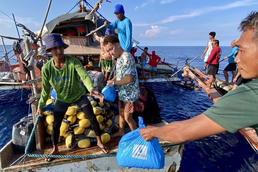 Filipino volunteers from the civilian-led relief mission Atin Ito (It’s Ours!) group distribute relief goods to fishermen aboard a motorised wooden boat on the waters of the disputed South China Sea, on May 16. Photo: EPA-EFE