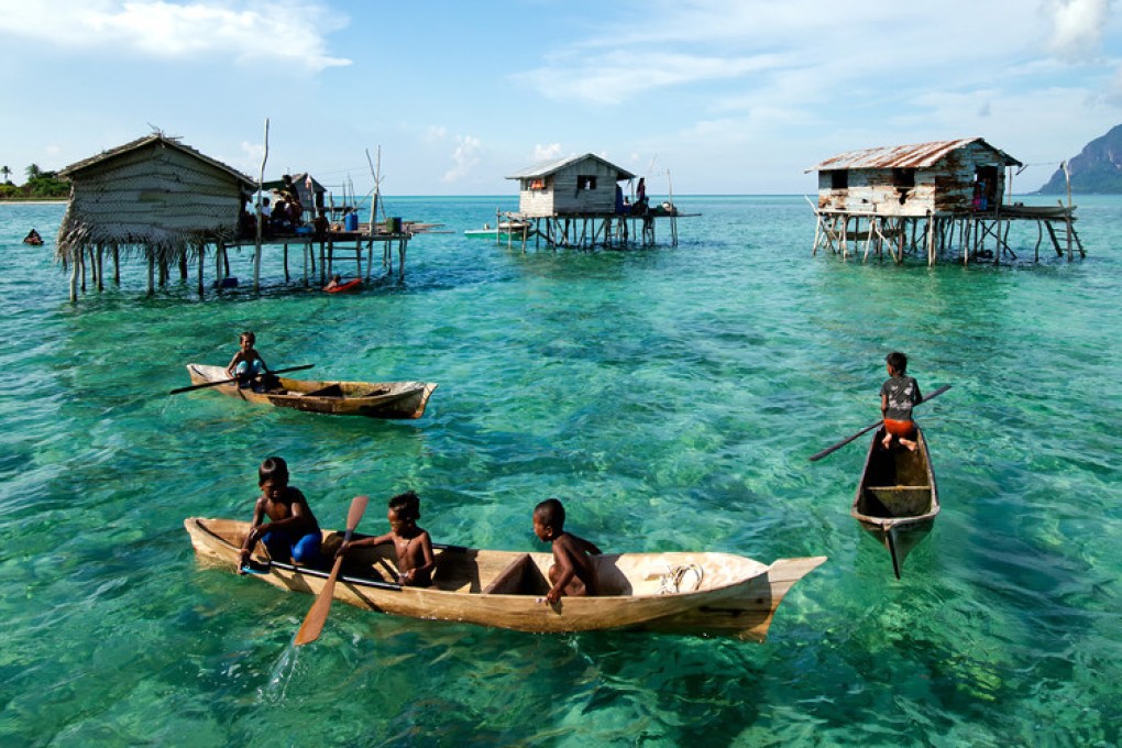 Young Bajau laut children paddle a boat near stilted houses off the coast of Borneo. Photo: Shutterstock