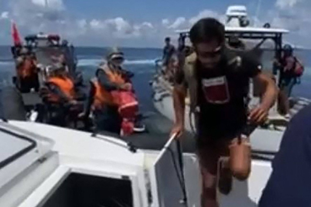 A Philippine navy serviceman boards a vessel while Chinese coastguard personnel (left) try to block it in the disputed South China Sea. Photo: PCG/AFP