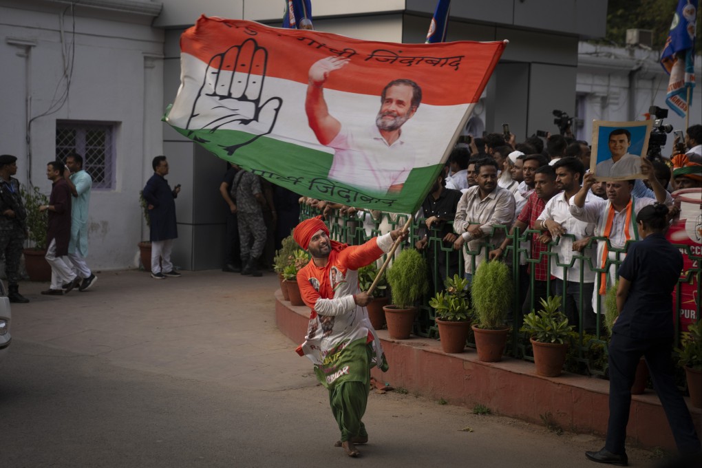 A Congress party supporter carries a flag printed with a portrait of party leader Rahul Gandhi at the party headquarters in New Delhi, India, on Tuesday. Photo: AP