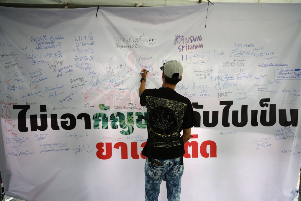 A marijuana enthusiast writes on a sign with a big message reading “Don’t take marijuana back to being a drug”, as they attend a demonstration over government’s plan to recriminalise cannabis, outside the UN Building in Bangkok, Thailand, on May 28. Photo: EPA-EFE