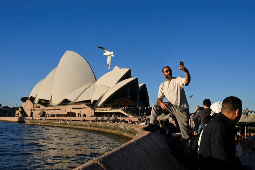 A man poses for a selfie in front of Australia’s Sydney Opera House last month. The leader of Australia’s opposition has blamed migrants for Australia’s housing shortage. Photo: Reuters