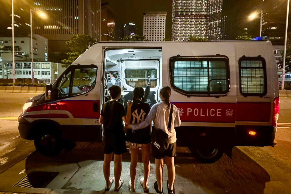 Officers escort one of the suspects to a police vehicle outside the S2O Hong Kong Songkran Music Festival at the Central harbourfront. Photo: Handout