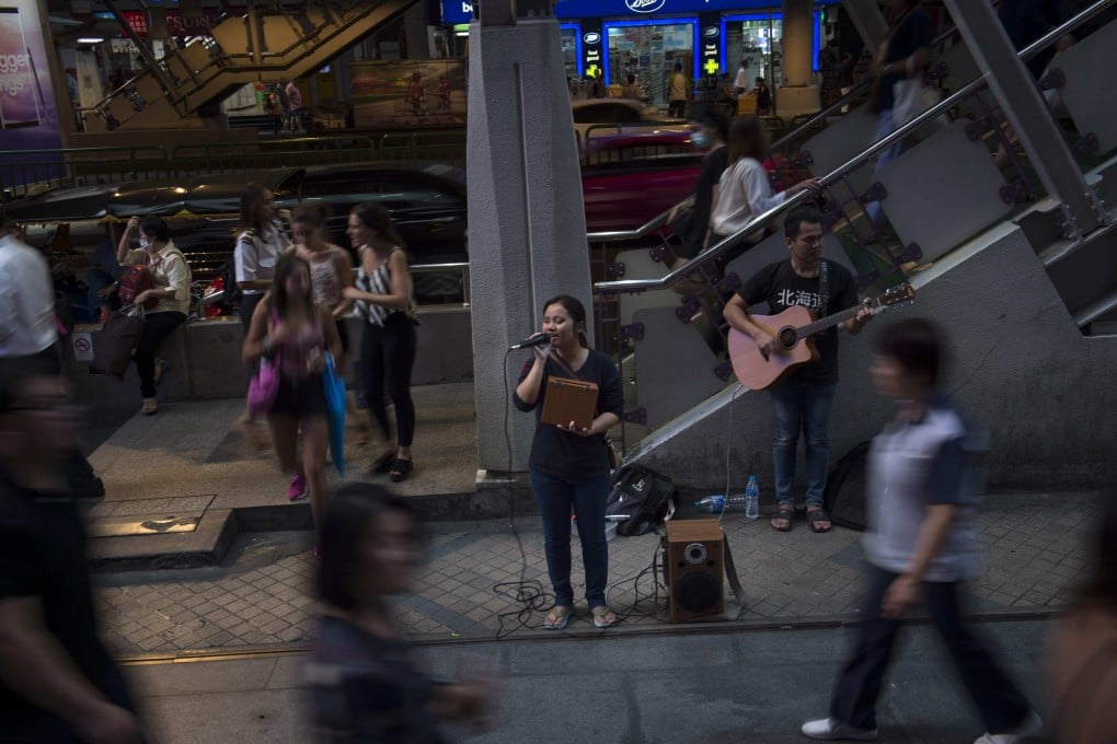 A blind singer performs in front of a skytrain station in Bangkok. Under Thai laws, begging can be punished by up to one-month imprisonment and/or a fine of up to 10,000 baht. Photo: AFP