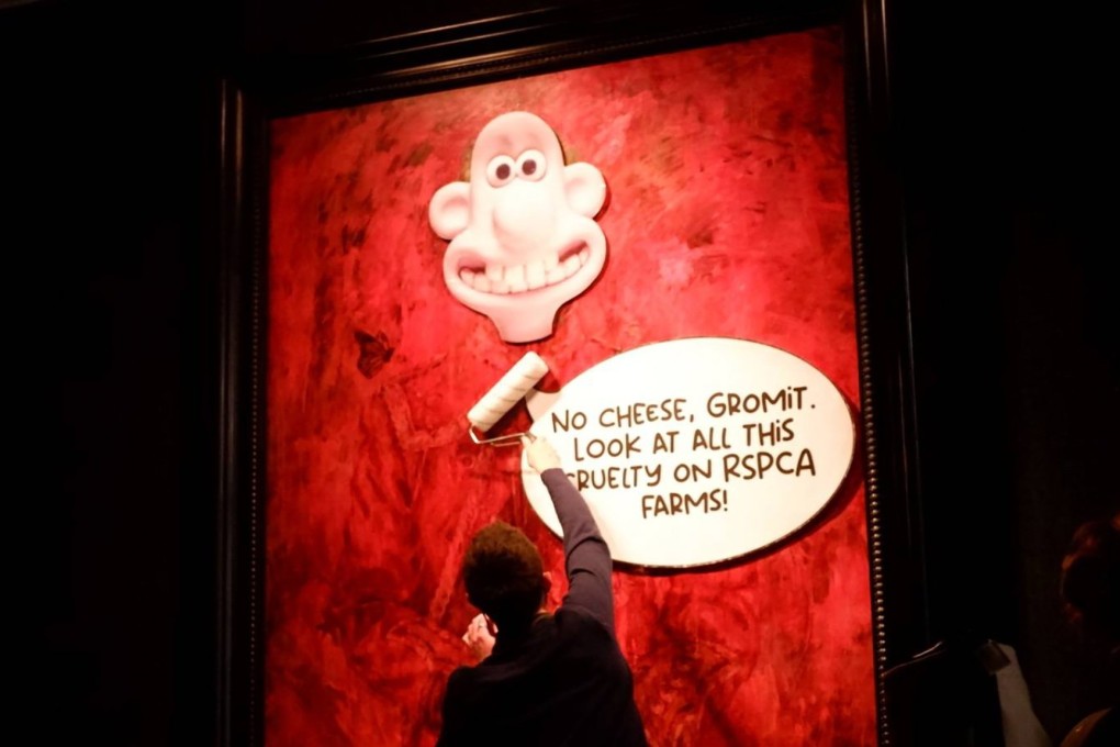 An activist puts the face of animated character Wallace over the painting of King Charles at the Philip Mould gallery in London on Tuesday. Photo: Animal Rising via EPA-EFE