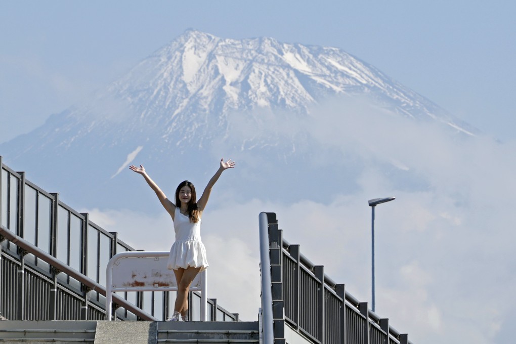 A tourist from Thailand poses on the Mount Fuji Dream Bridge in Fuji City, where authorities plan to erect a fence to stop visitors blocking the road to snap their dream photo. Photo: EPA-EFE