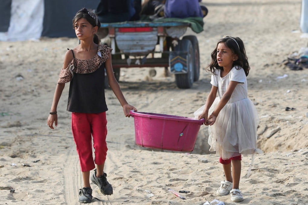 Girls walk carrying a container as Palestinians flee Rafah due to an Israeli military operation. Photo: Reuters