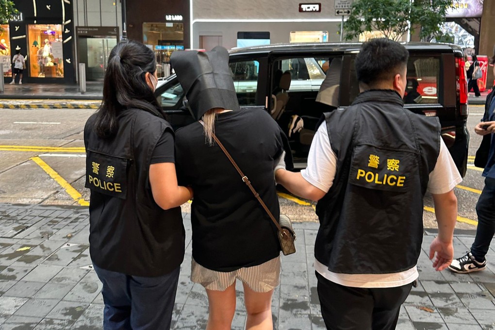 Police with one of the suspects arrested following the investigation into the phone scam. Photo: Handout