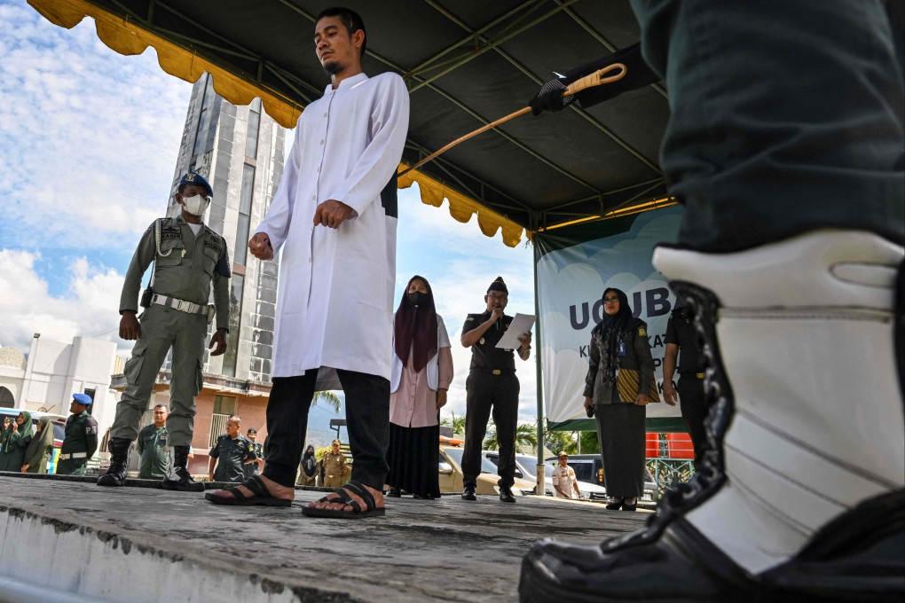 Indonesia’s religious police canes a man for using online gambling, in front of Al Munawwarah mosque in Jantho, Aceh province. Gambling is illegal in Indonesia. Photo: AFP