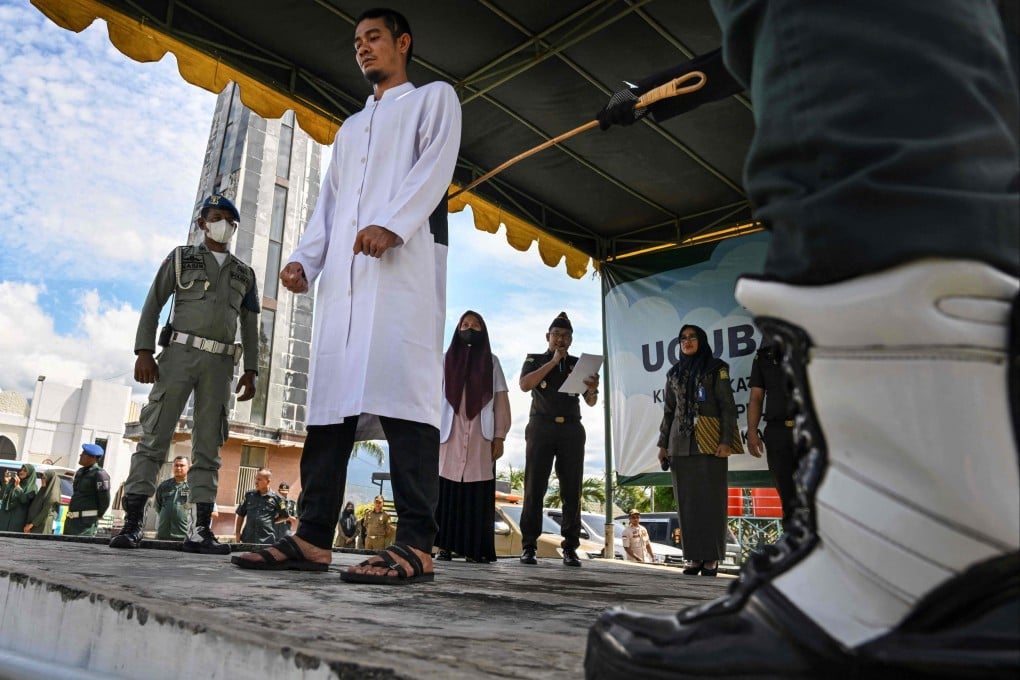 Indonesia’s religious police canes a man for using online gambling, in front of Al Munawwarah mosque in Jantho, Aceh province. Gambling is illegal in Indonesia. Photo: AFP