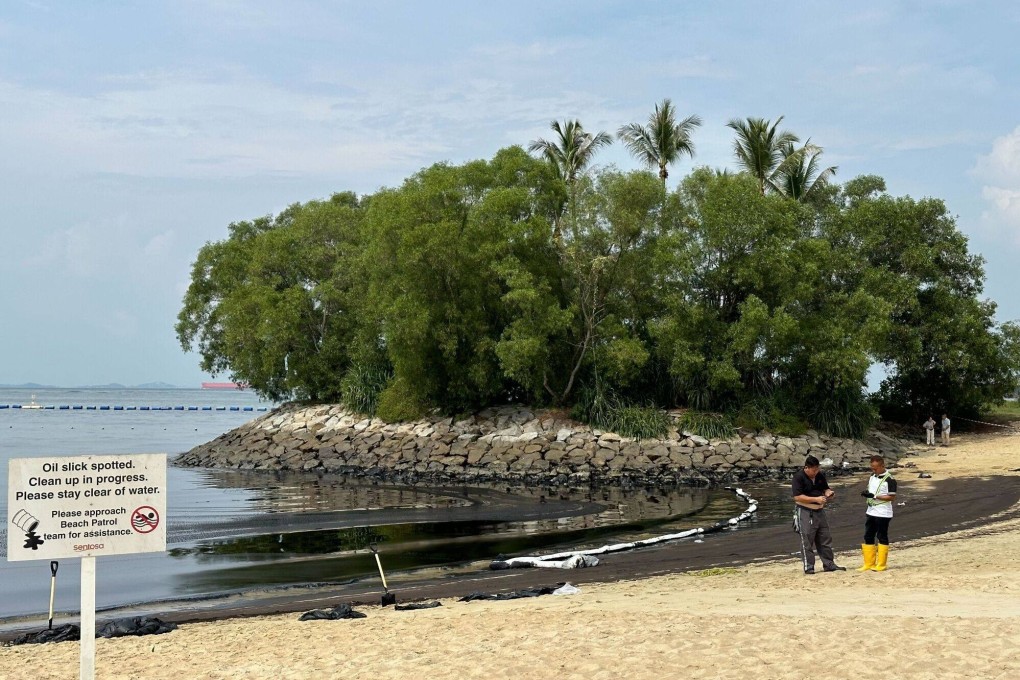Clean-up crew next to oil-coated sand and rocks along the Tanjong Beach on Sentosa island in Singapore on June 15. Photo: Bloomberg