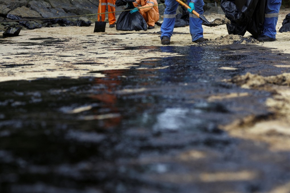 Workers clean up the oil slick on Sentosa Island’s Tanjong Beach in Singapore on Sunday. Photo: Reuters