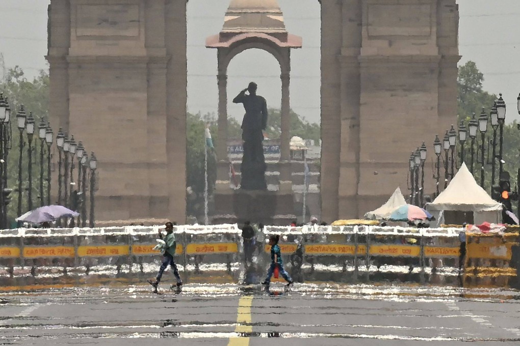 People walk past a mirage in front of the India Gate during a hot summer day in New Delhi on Monday. Photo: AFP