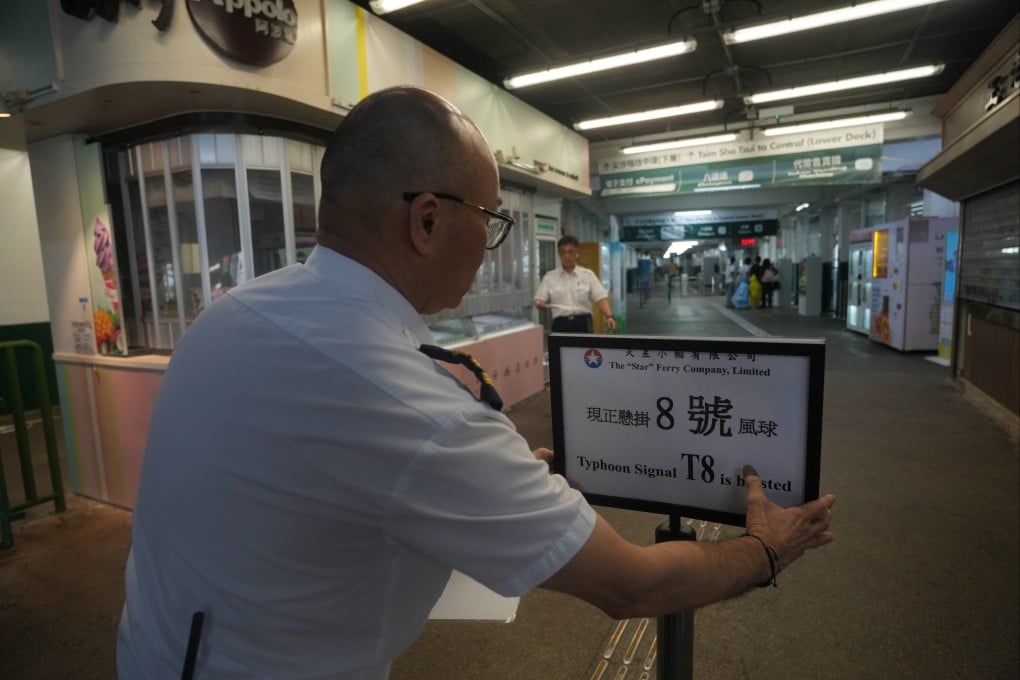 A worker at the Star Ferry pier in Tsim Sha Tsui puts up a sign to warn people about a No 8 typhoon warning on October 8, 2023. Photo: Sam Tsang