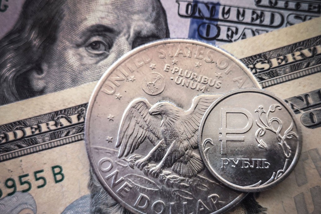 A Russian rouble coin is pictured with US dollar bills. Photo: AFP