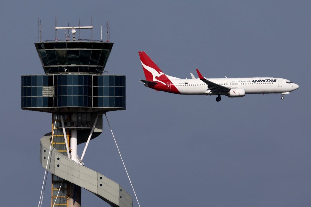 A Qantas Airways passenger plane makes its final approach for landing in front of a control tower at Sydney International Airport. Photo: AFP