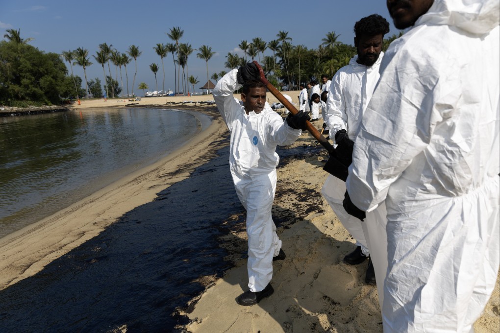 Workers clean up an oil slick at Tanjong Beach in Sentosa. Photo: EPA-EFE