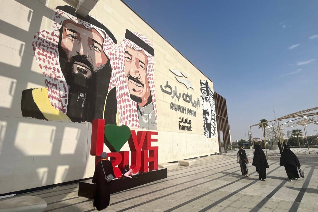 Saudi women walk past a mural depicting Saudi King Salman bin Abdulaziz (centre) and his son Crown Prince Mohammed bin Salman (left) at a park in the capital Riyadh. Photo: AFP