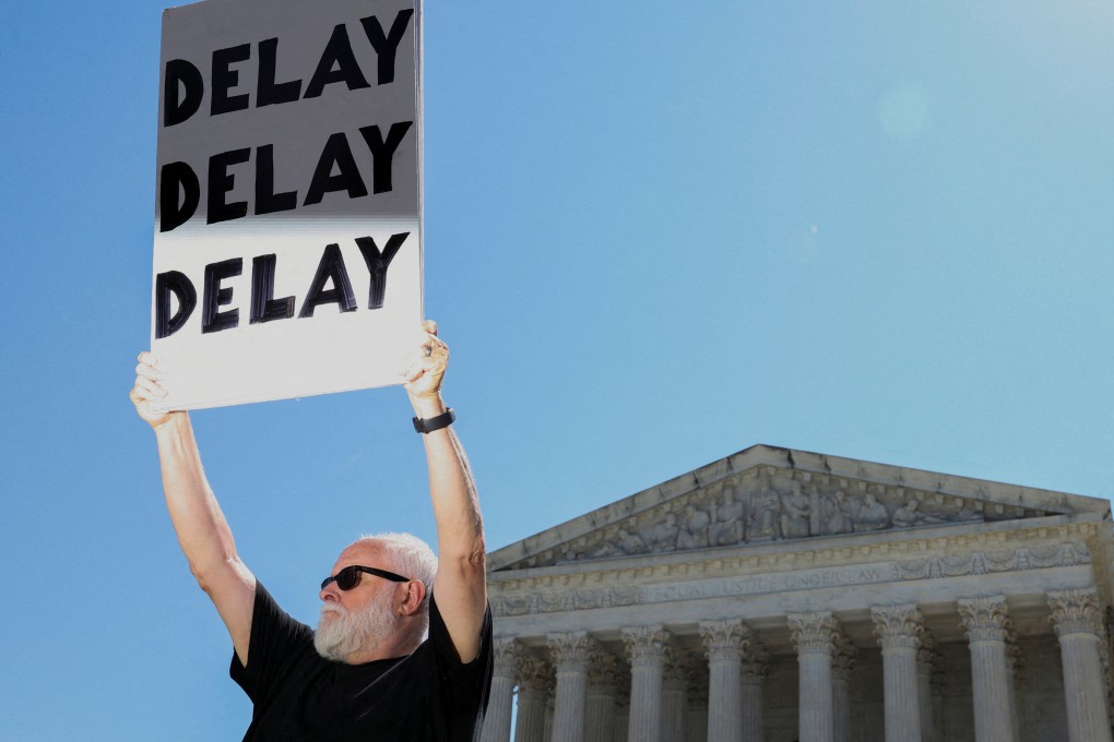 A protester holds a sign that reads “Delay Delay Delay” outside the US Supreme Court on Friday. Photo: AFP