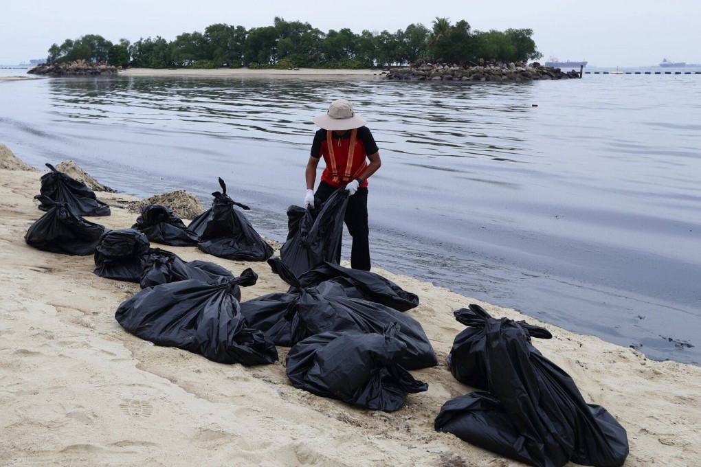 A clean up crew handles a bag of oil coated sand along the Tanjong Beach on Sentosa Island, Singapore, on June 15. Photo: Blooomberg