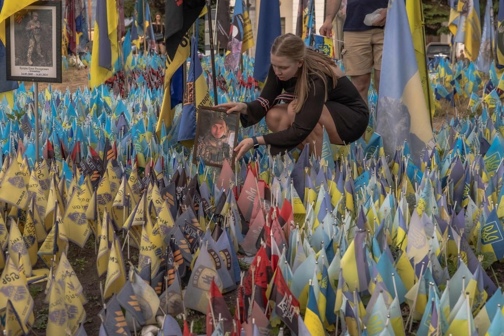 A woman displays a portrait of a Ukrainian serviceman in a memorial area to fallen Ukrainian and foreign fighters at Kyiv’s Independence Square on May 27. Photo: AFP