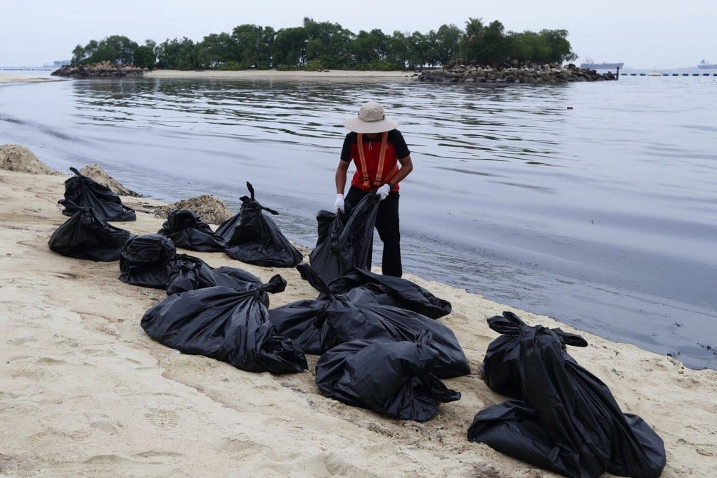A member of the clean-up crew handles oil-coated sand along Tanjong Beach on Singapore’s Sentosa Island on June 15. Photo: Bloomberg