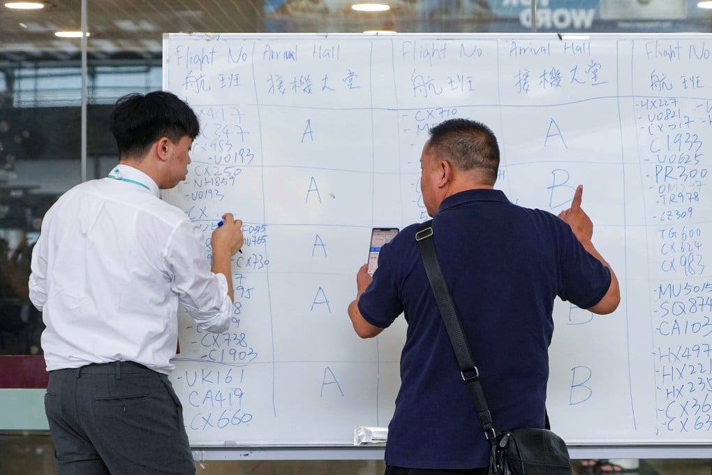 Airport staff write departure times and gate numbers on whiteboards with marker pens during the computer glitch on Sunday. Photo: Elson Li