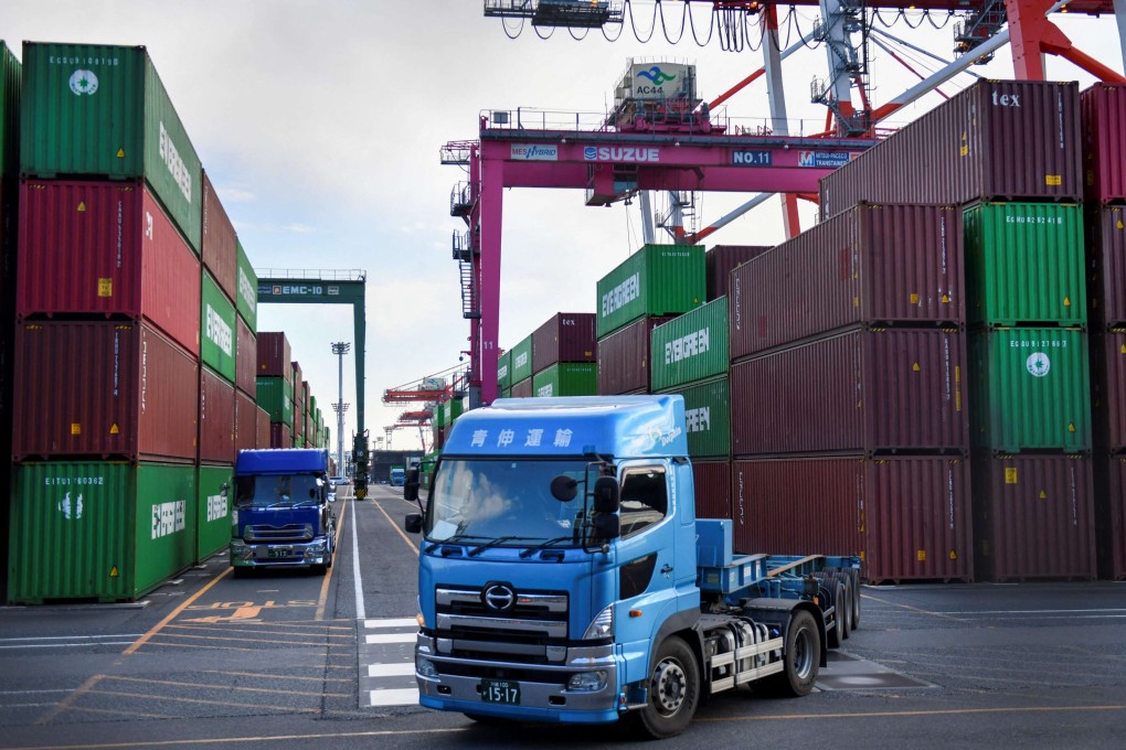 A truck pulls out of a port in Tokyo as cargo containers are loaded on and off vehicles. Photo: AFP