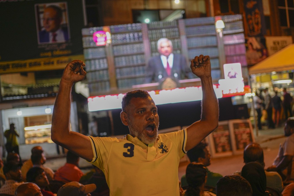 A supporter of Sri Lanka’s President Ranil Wickremesinghe cheers as he watches the president’s televised announcement of the country’s debt restructuring agreements on June 26. Photo: AP