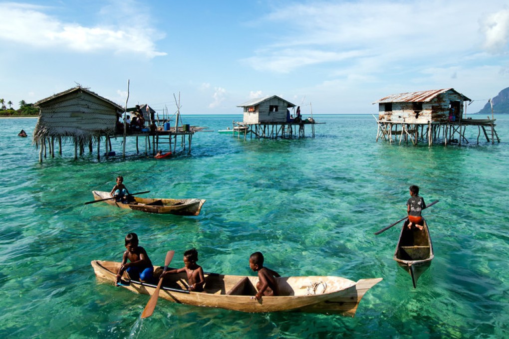 Young Bajau laut children paddling a boat near stilted houses off the coast of Borneo. Photo: Shutterstock