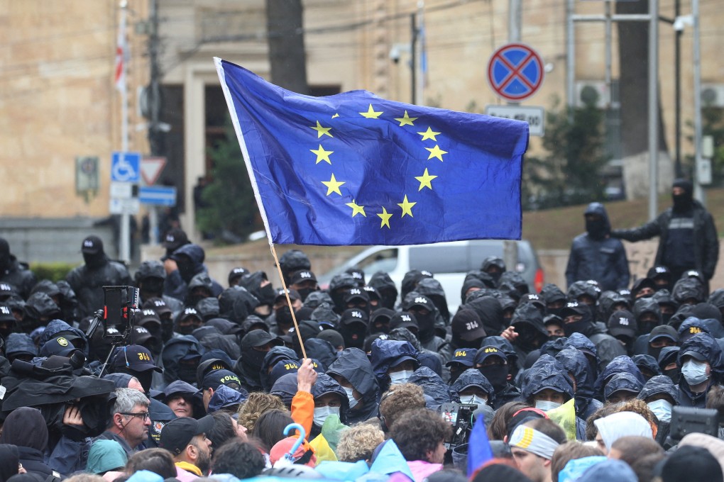 A demonstrator holds a European Union flag in front of law enforcement officers during a rally to protest against a bill on “foreign agents” in Tbilisi in May. Photo: Reuters