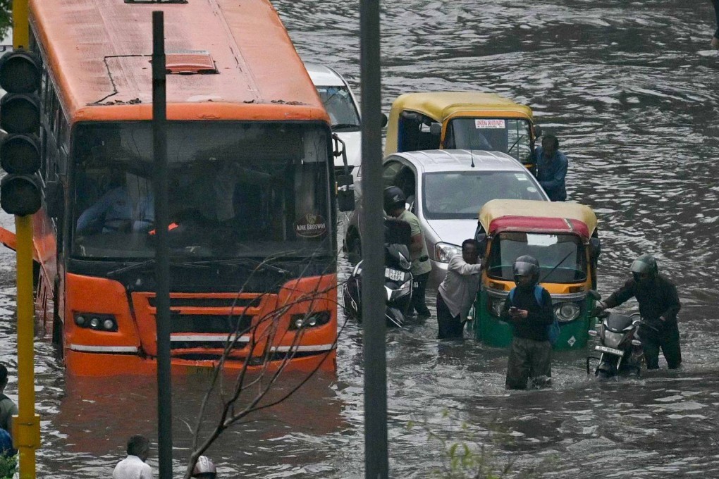 Commuters wade through flooded streets after heavy rains in New Delhi on Friday. Photo: AFP