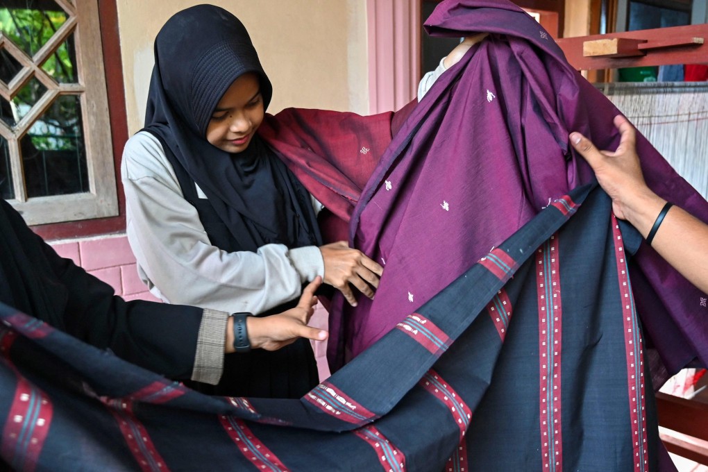 An employee displays traditional textiles in Lhoknga, Aceh province on June 24. The labour-heavy textile sector employs around 3.9 million people in Indonesia. Photo: AFP