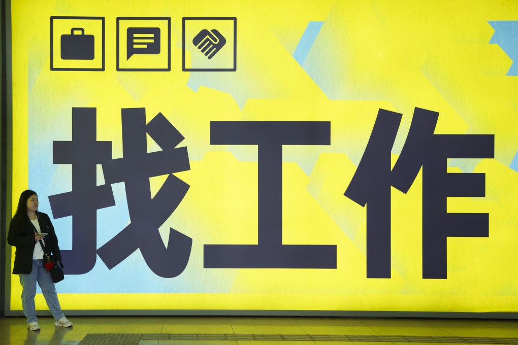 A Chinese woman stands in front of a billboard with the words “looking for a job” at a subway station in Beijing. Photo: AP Photo