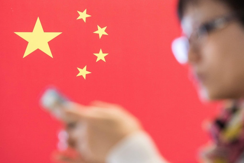 A woman checks her smartphone in front of a Chinese flag at a computer fair in Hanover, Germany, in March 2015. Ultranationalist views are increasingly being aired on Chinese social media, leading to real-life consequences. Photo: EPA