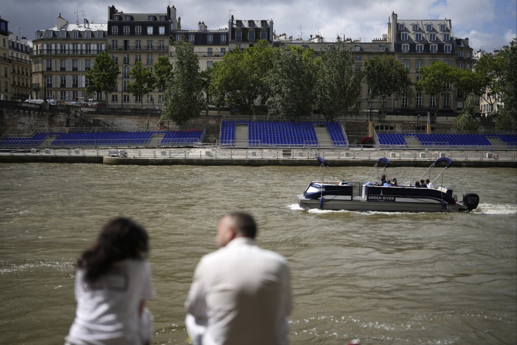 People sit along the Seine River with stands installed on its banks. The river will host the Paris Olympic Games opening ceremony on July 26. Photo: AP