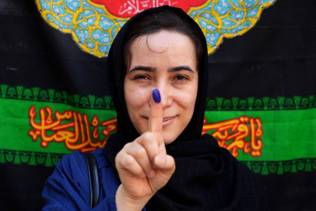 An Iranian woman displays her ink-stained finger after casting her ballot. Photo: AFP