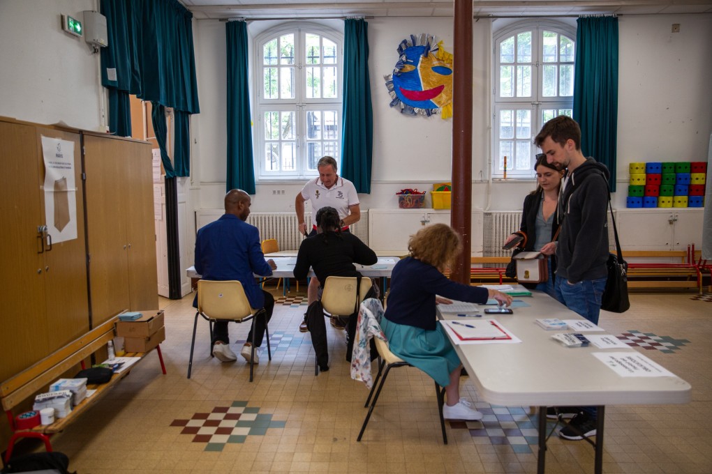 Polling officials attend to voters during the second round of French parliamentary elections, at a polling station in Paris, France, on Sunday. Photo: EPA-EFE