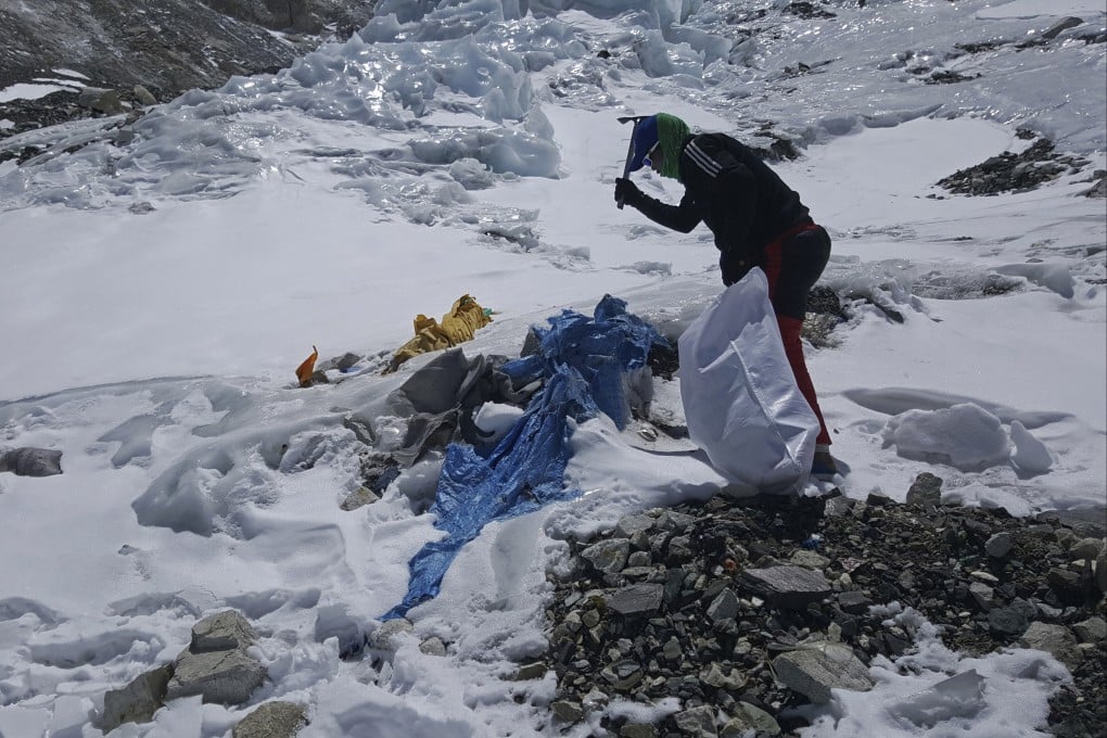 A member of the Nepal government-funded team uses a spade to remove frozen trash en route the Mount Everest in 2021. Photo: Peak Promotion via AP