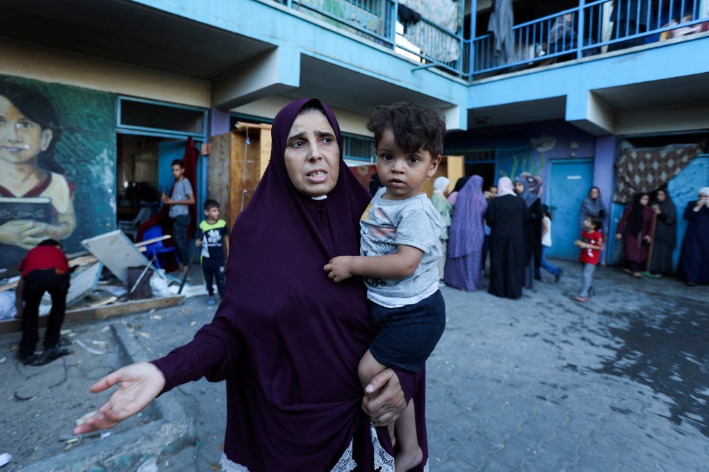 A Palestinian woman carrying a child reacts after an Israeli air strike on a school sheltering displaced people in al-Nuseirat on Saturday. Photo: Reuters
