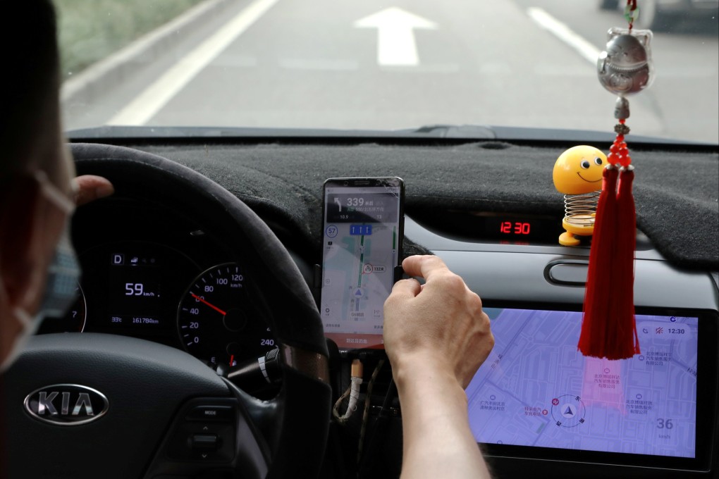 A driver of Chinese ride-hailing service Didi drives with a phone showing a navigation map on Didi’s app in Beijing. Photo: Reuters