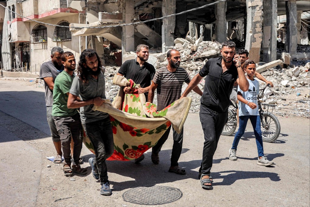 Men in the Tuffah district east of Gaza City carry a body in a blanket on Monday. Photo: AFP