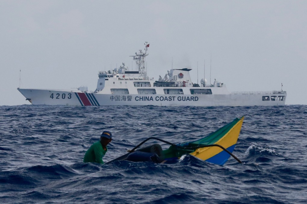 A China Coast Guard patrol ship manoeuvres near a Filipino fisherman aboard a motorised wooden boat sailing towards Scarborough Shoal in the disputed South China Sea in May. Photo: EPA-EFE