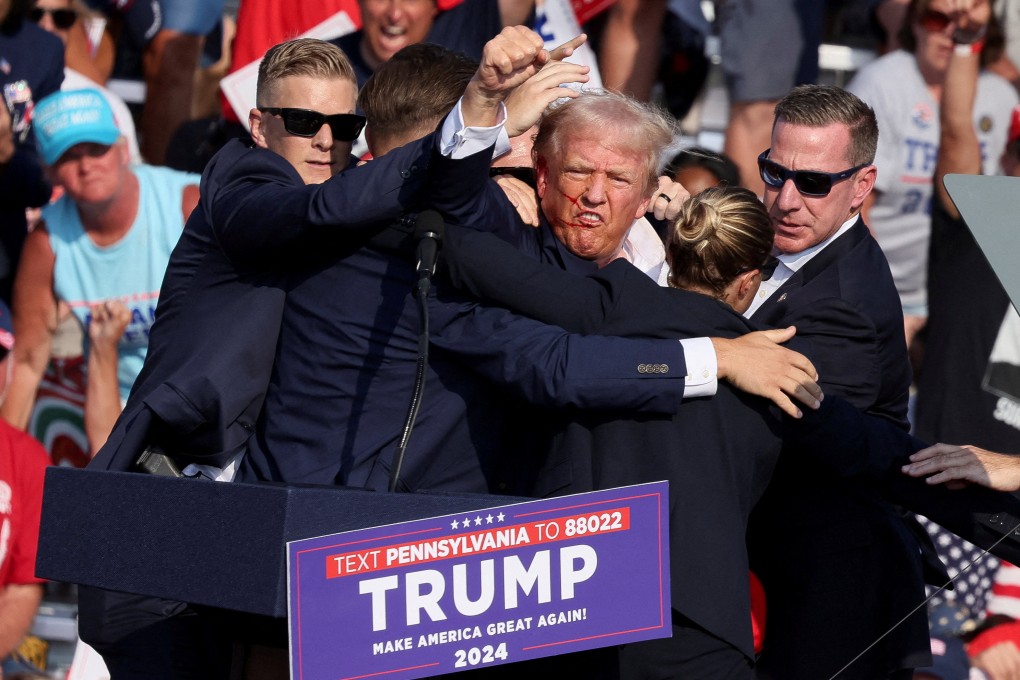 Republican presidential candidate and former U.S. President Donald Trump raises his fist while he is assisted by US Secret Service personnel after he was shot in the right ear during a campaign rally in Butler, Pennsylvania, on July 13. Photo: Reuters